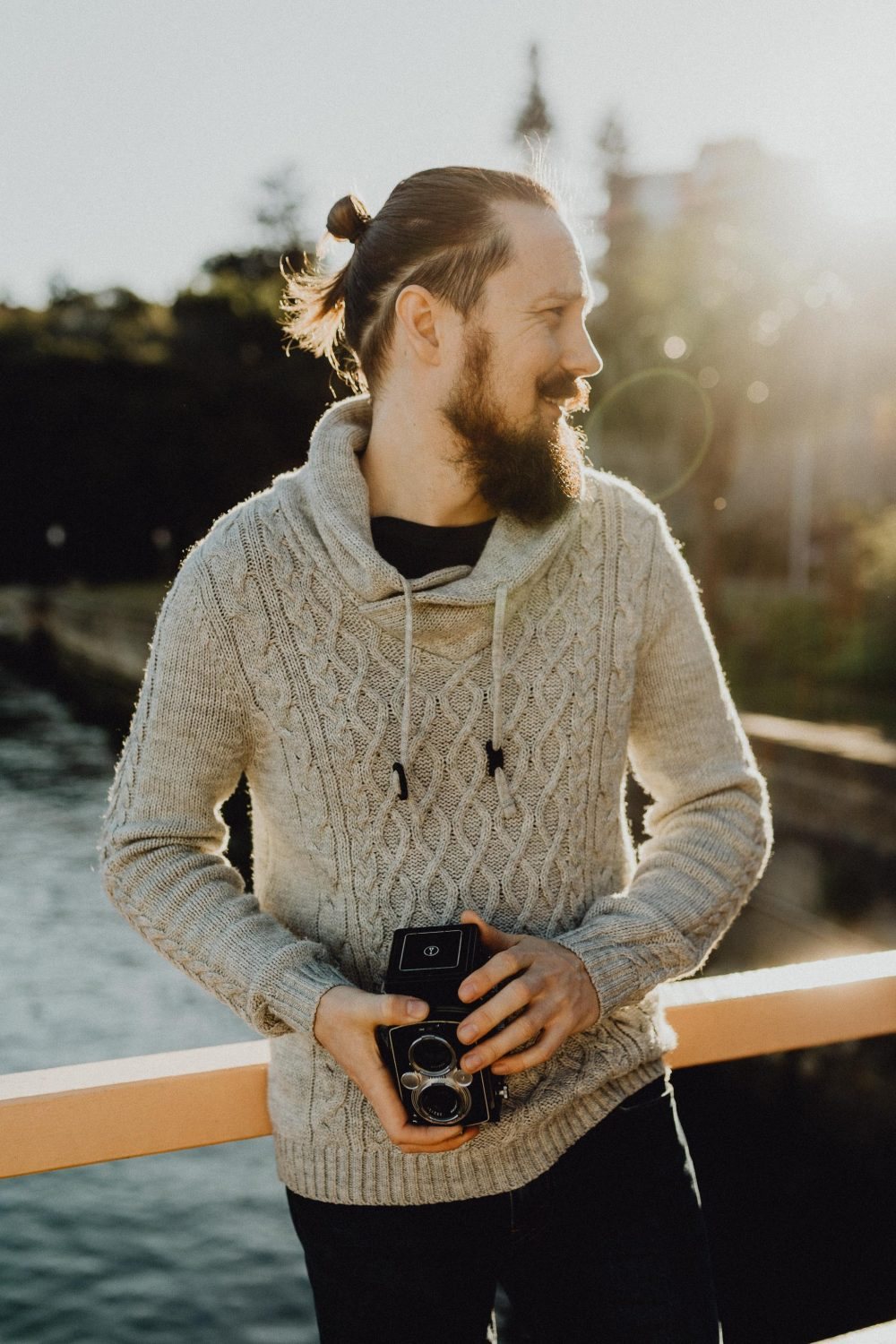 Anton on a boat in harbour light, holding a film camera at his chest
