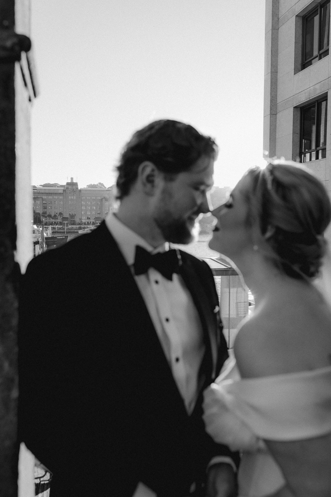 A couple nose to nose by a window, in black and white
