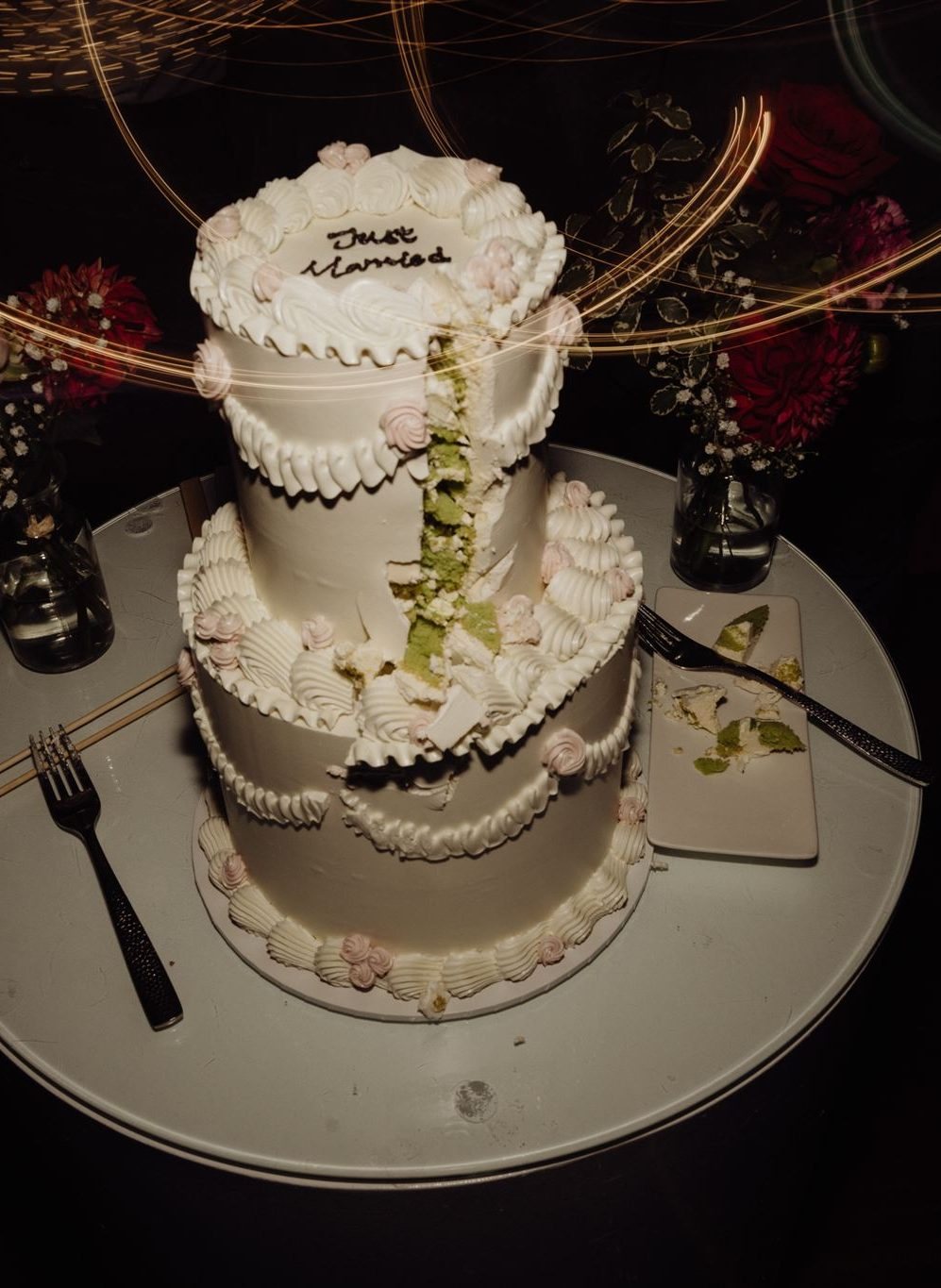 A white piped wedding cake on a table in warm night light