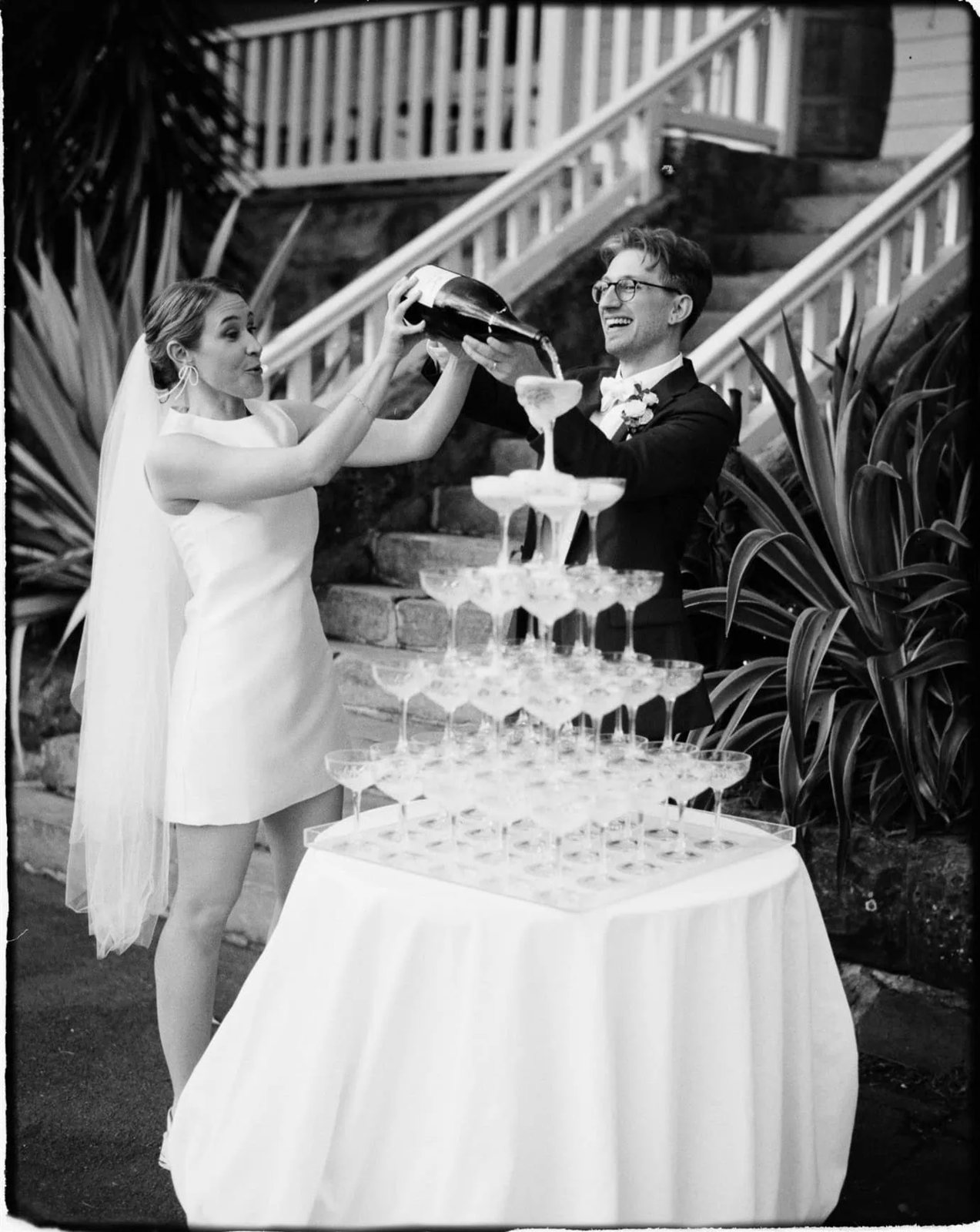 The couple pouring champagne into a glass tower, a black and white film frame
