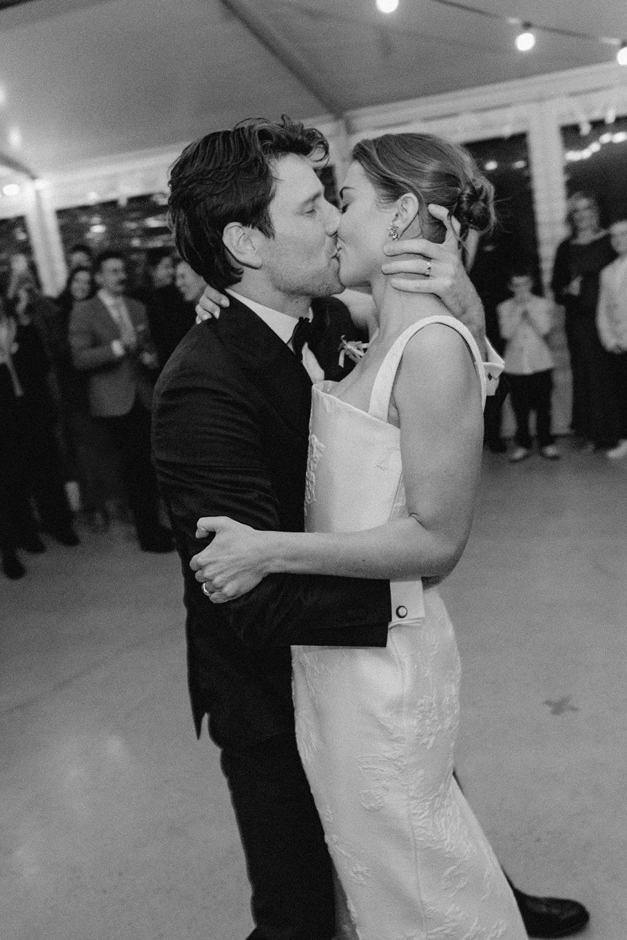 A couple kissing on a crowded dance floor, in black and white